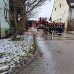 Einsatzkräfte mit Schlauchleitung vor dem Anwesen