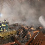 Einsatzkräfte löschen mithilfes eines Baggers