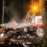 Einsatzkräfte löschen mithilfe eines Baggers